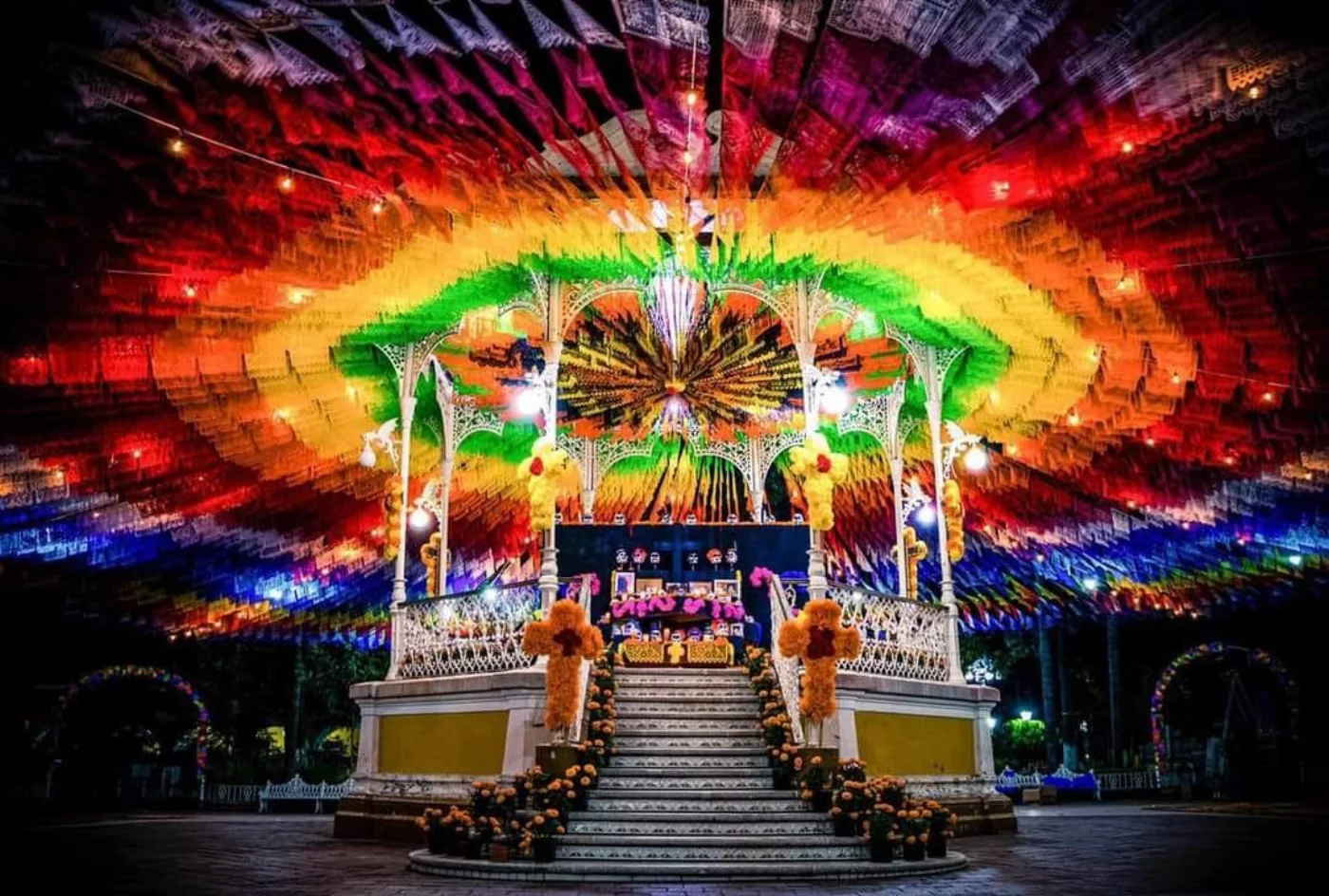 Vista completa de dosel de papel picado cubriendo plaza con iluminación festiva