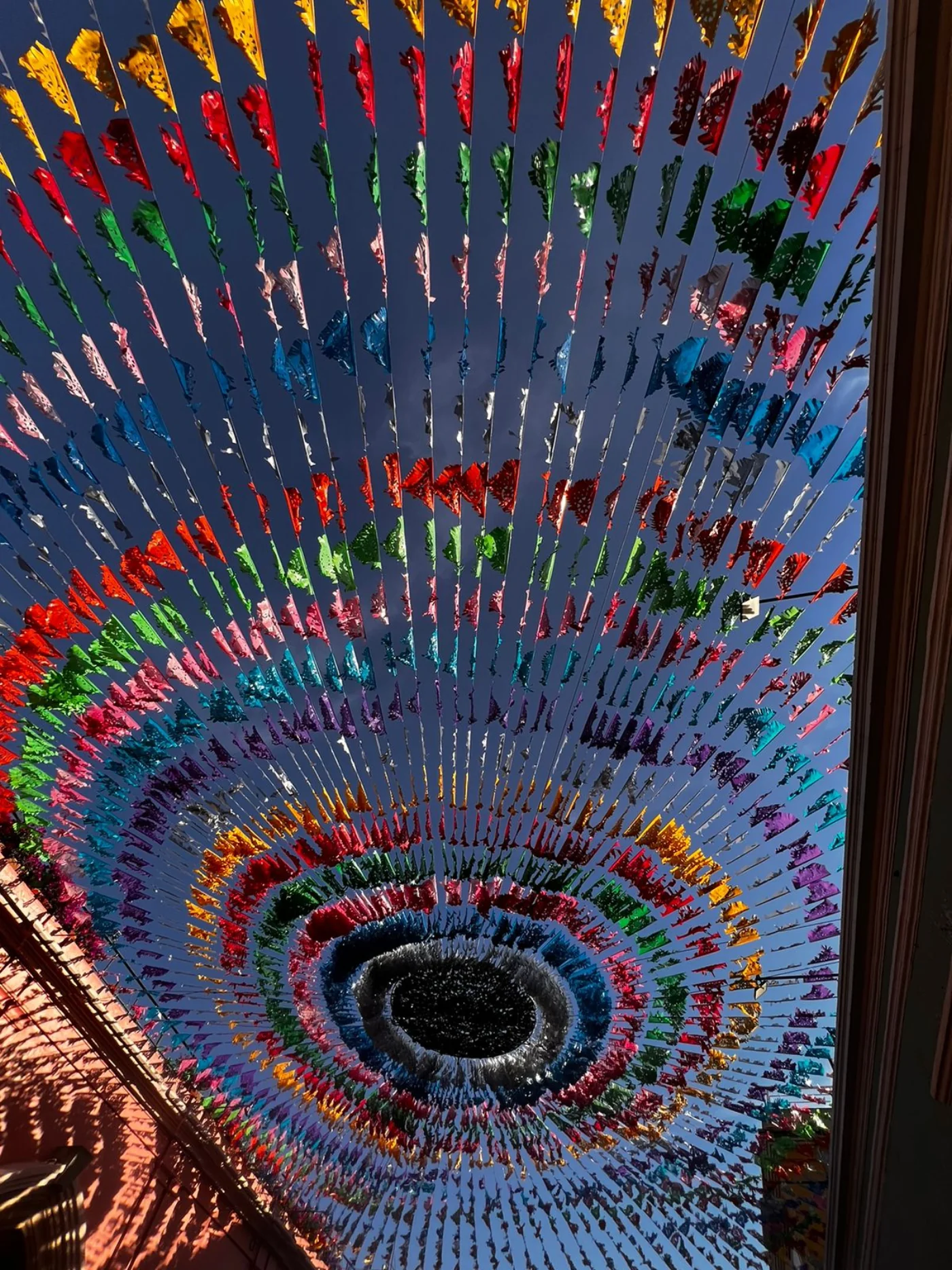 Instalación en espiral de papel picado vista desde abajo contra el cielo azul