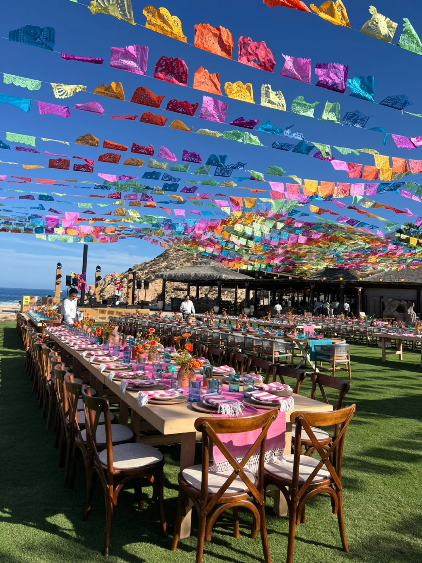 Evento en resort de playa decorado con papel picado artesanal — mesa larga frente al mar