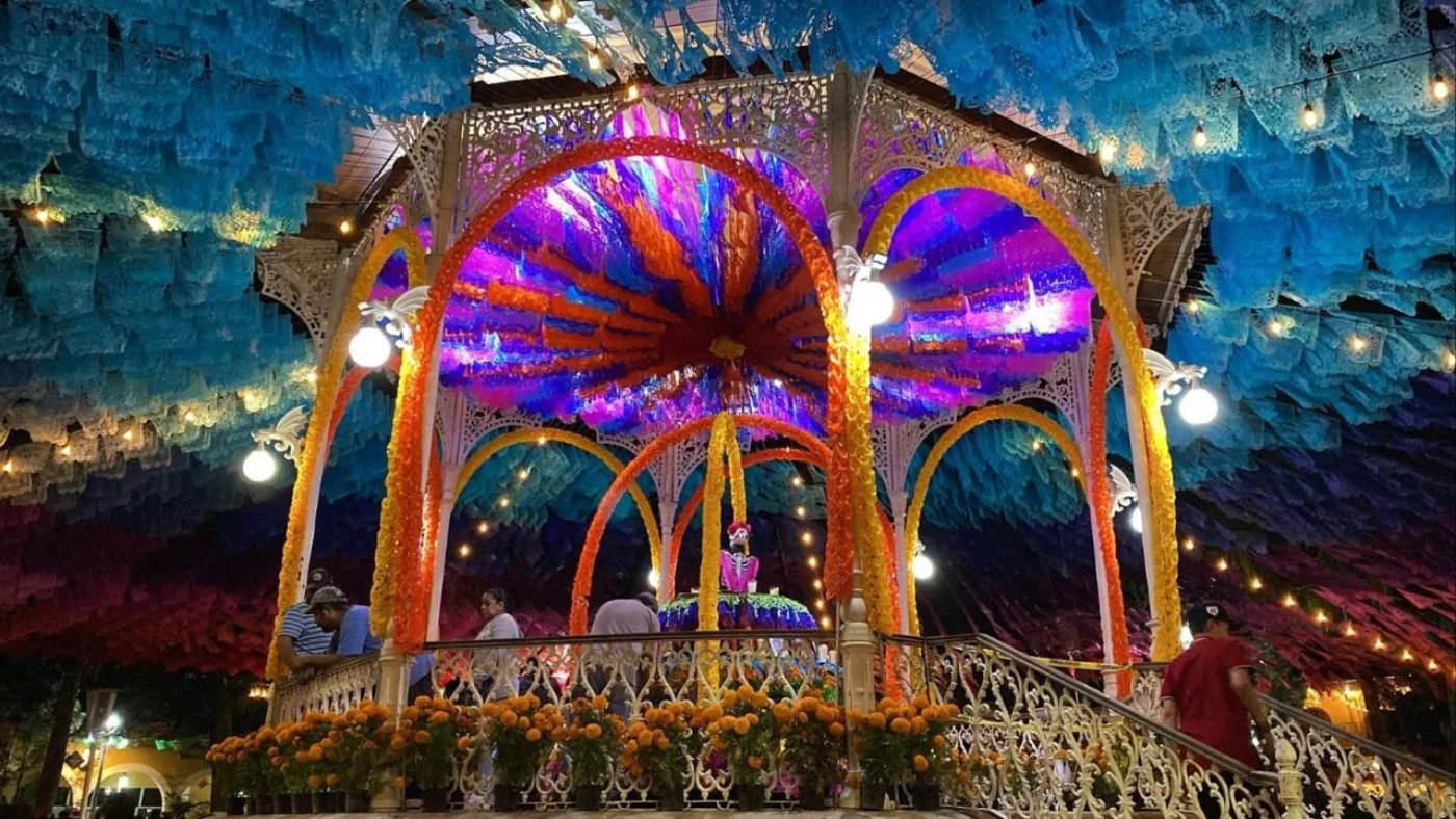 Kiosco con dosel de papel picado turquesa y azul iluminado de noche